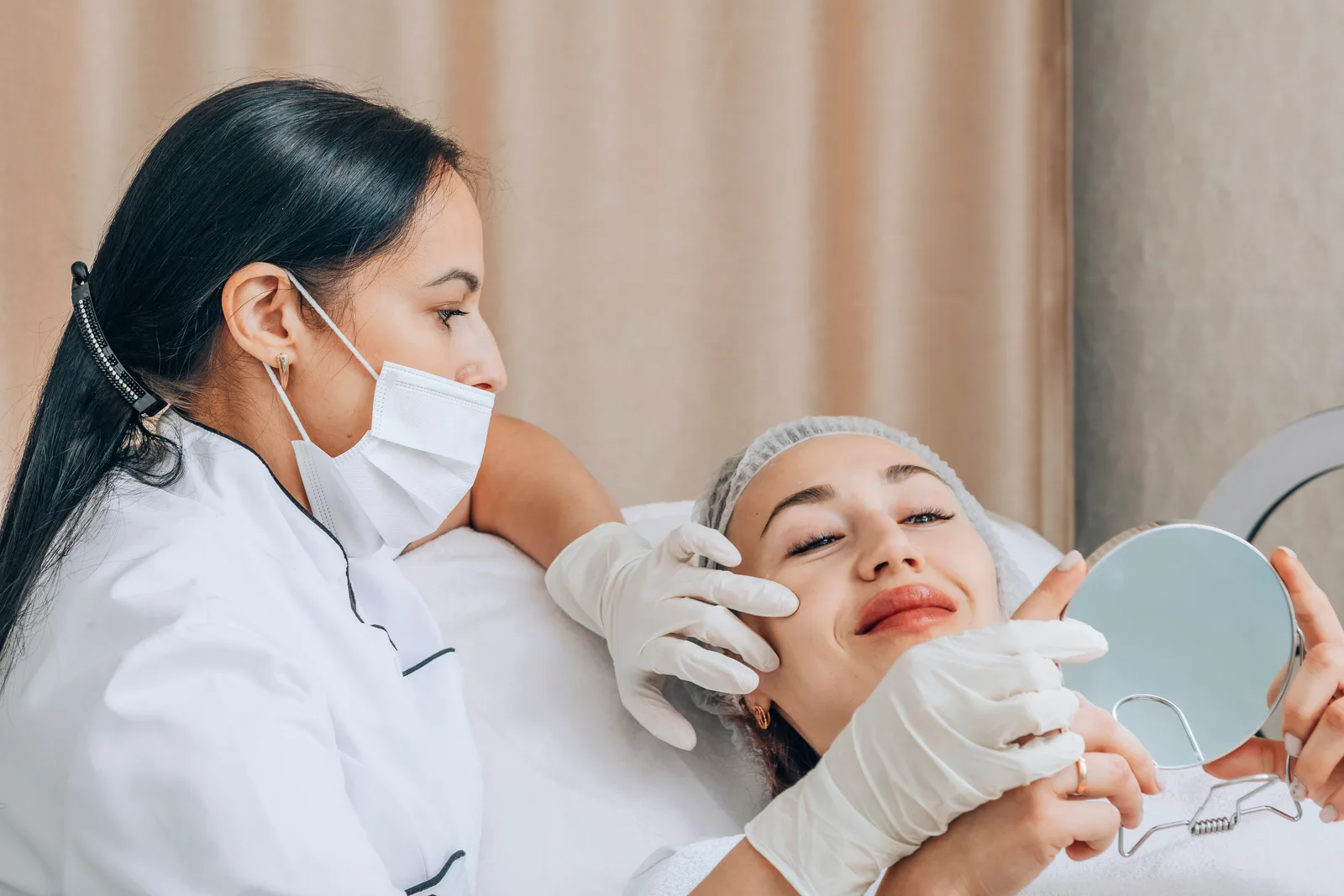 Dermatology clinician examining a patient's face with a mirror