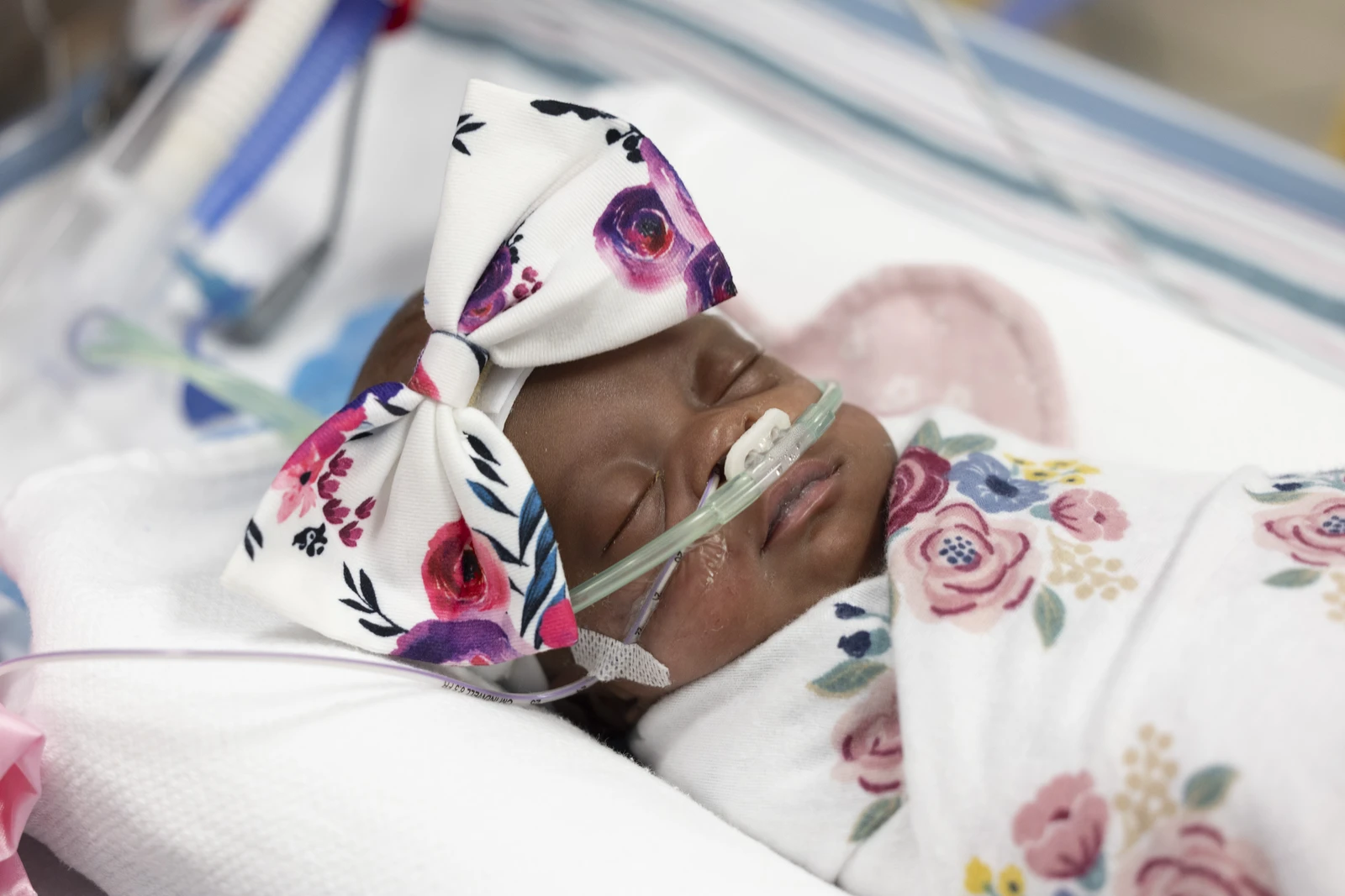 A sleeping newborn wrapped in a floral blanket in a hospital setting